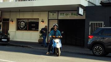 A person on a scooter in front of a building with a sign that reads '82 on Reg.'