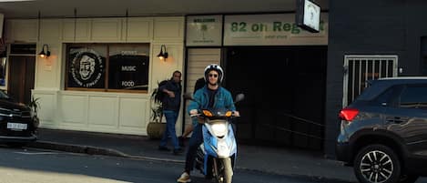 A person on a scooter in front of a building with a sign that reads '82 on Reg.'