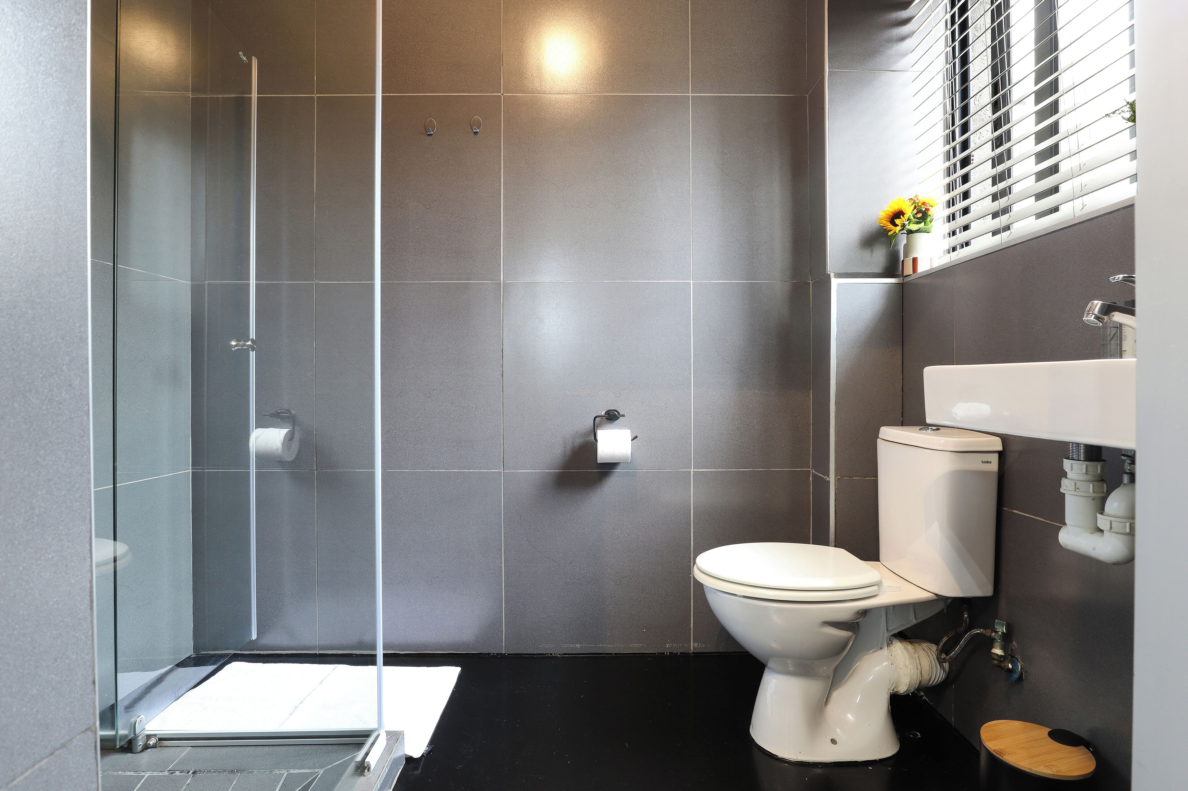 Un baño moderno con cabina de ducha de vidrio, inodoro y lavabo con espejo.