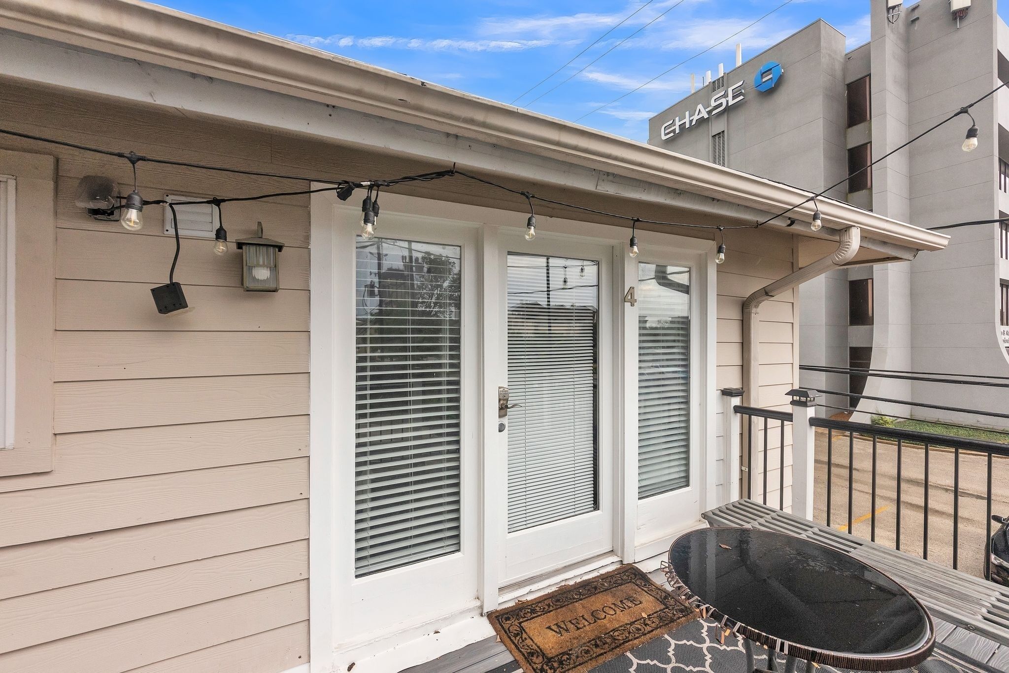 A house with a covered porch, a welcome mat, and a small table.