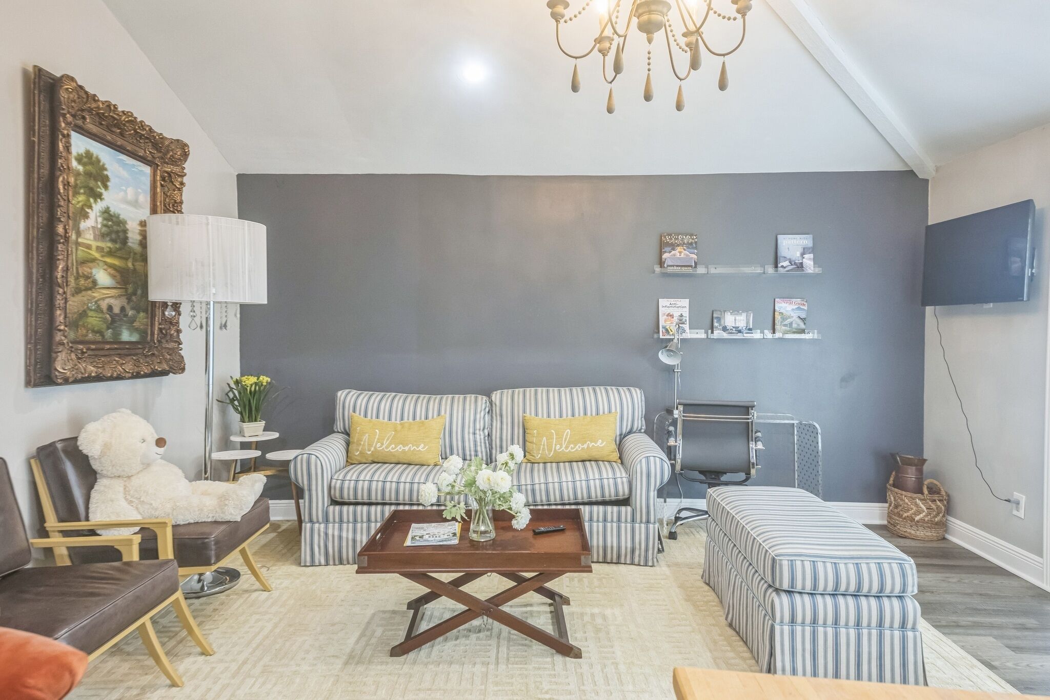 A living room with a sofa, chairs, a coffee table, a TV, and a bookshelf.