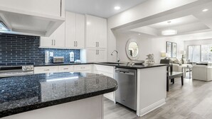 Une cuisine moderne avec des meubles blancs, un plan de travail en granit et un lave-vaisselle encastré.