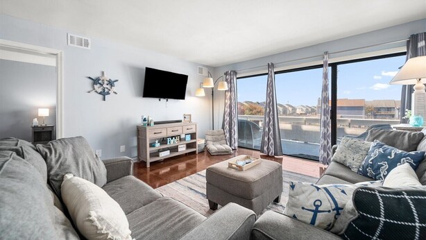 A modern living room with a large window, a flat-screen TV, and a wooden console table. - 2 bedroom, 2 bath, 28th bayside with pool and tennis court! (Ocean City)