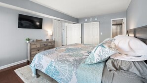 A bedroom with a bed, dresser, TV, and two doors. - 2 bedroom, 2 bath, 28th bayside with pool and tennis court! (Ocean City)