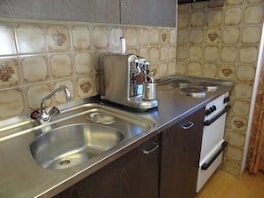 A kitchen with a stainless steel countertop, a coffee maker, a sink, and an oven. - Sunnmatt Süd Wohnung 631 Appartement/Fewo 5-Bettwohnung by Interhome (Engelberg)