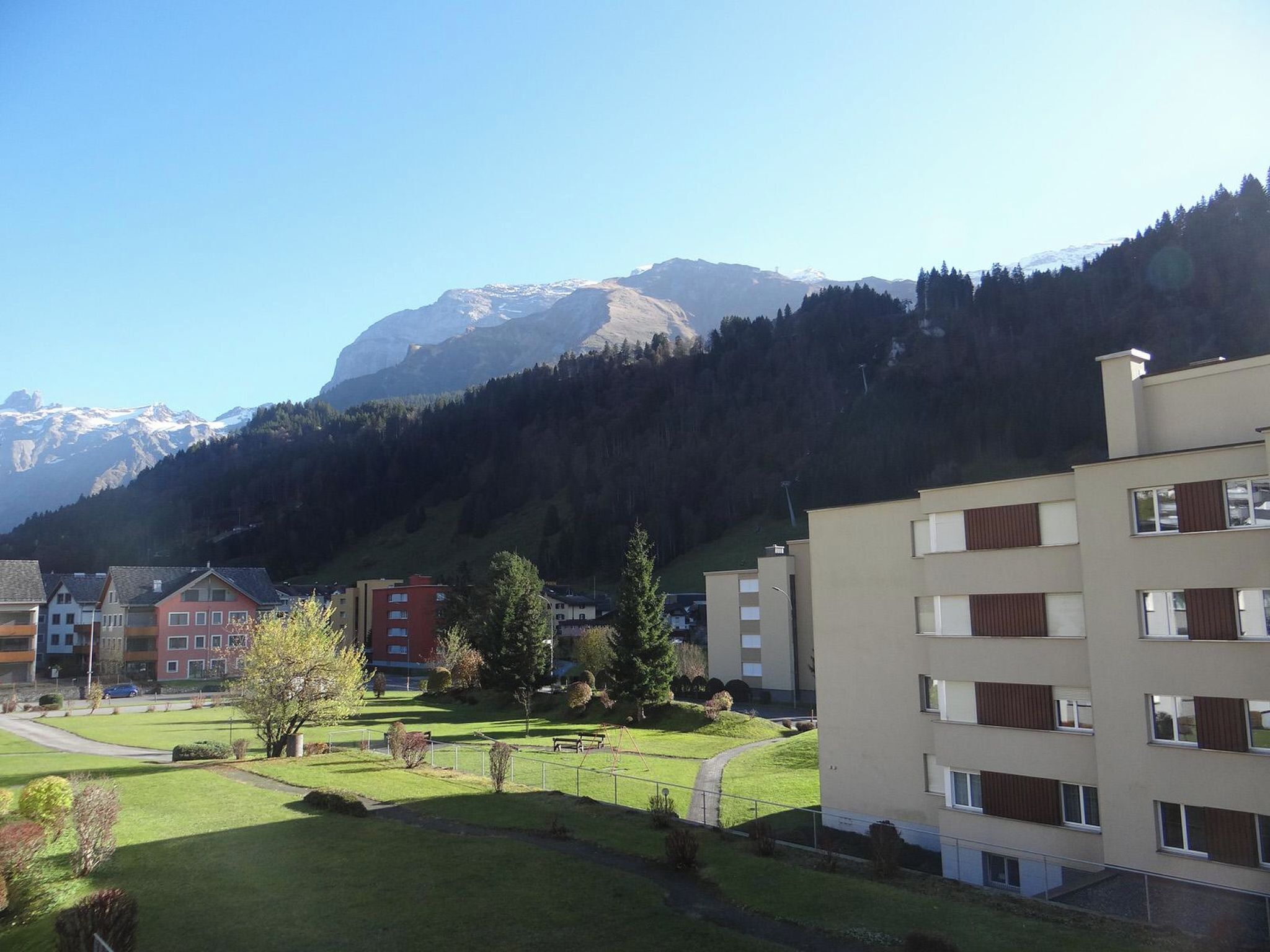 Un quartier résidentiel avec une vue sur les montagnes, caractérisé par des bâtiments modernes dotés de balcons et une pelouse bien entretenue.