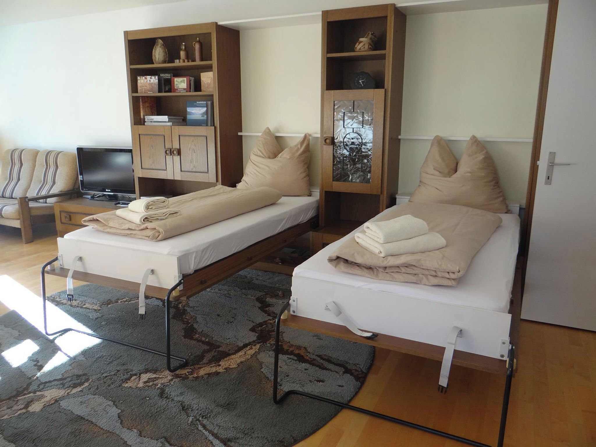 Ein Zimmer mit zwei Betten, einem Fernseher und einem Bücherregal.