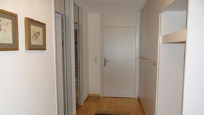 Un couloir avec un plancher en bois, des murs blancs et une porte au fond.