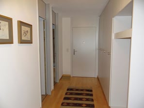A hallway with a wooden floor, white walls, and a door at the end. - Sunnmatt Süd Wohnung 631 Appartement/Fewo 5-Bettwohnung by Interhome (Engelberg)