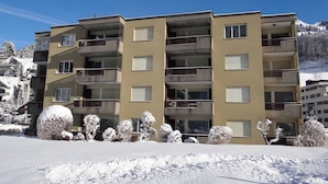 Un hôtel à plusieurs étages doté de balcons, un paysage enneigé et une montagne en arrière-plan.