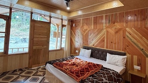 Une chambre à coucher avec un lit, des murs en bois, un sol à motifs et de grandes fenêtres.
