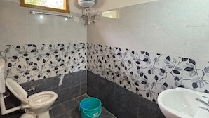 Une salle de bain avec des toilettes, un lavabo et une fenêtre située au-dessus des toilettes.