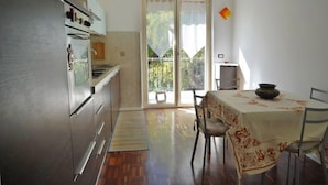 A kitchen with a dining table, chairs, and a view of the outdoors. - Balcony Flat Near the Center by Wonderful Italy (Sanremo)