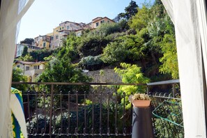 En balkon med udsigt til et område med etplanshuse og frodig vegetation.