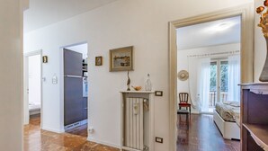 A spacious room with a bed, a chair, and a small table with decorative items. - Balcony Flat Near the Center by Wonderful Italy (Sanremo)