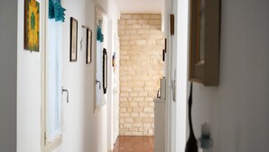 A hallway with a stone wall, framed pictures, and a door with a towel hanging on it. - Balcony Flat Near the Center by Wonderful Italy (Sanremo)