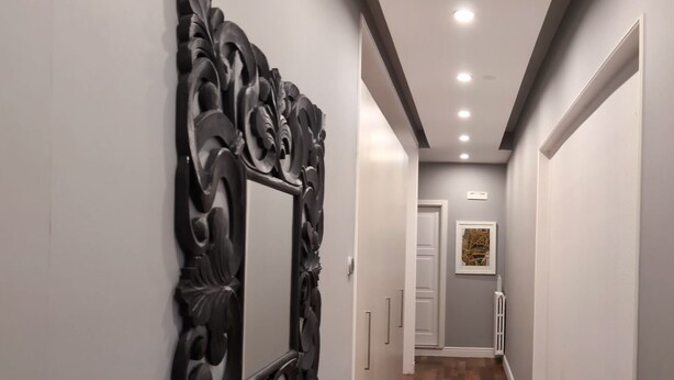 A hallway with a decorative wall mirror, wooden flooring, and a door at the end. - Superior Double Room (Avellino)