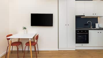 Una cocina moderna con armarios blancos, un horno negro y una mesa blanca con sillas rojas.