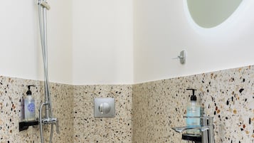 A bathroom with a freestanding toilet, a sink, and a shower.