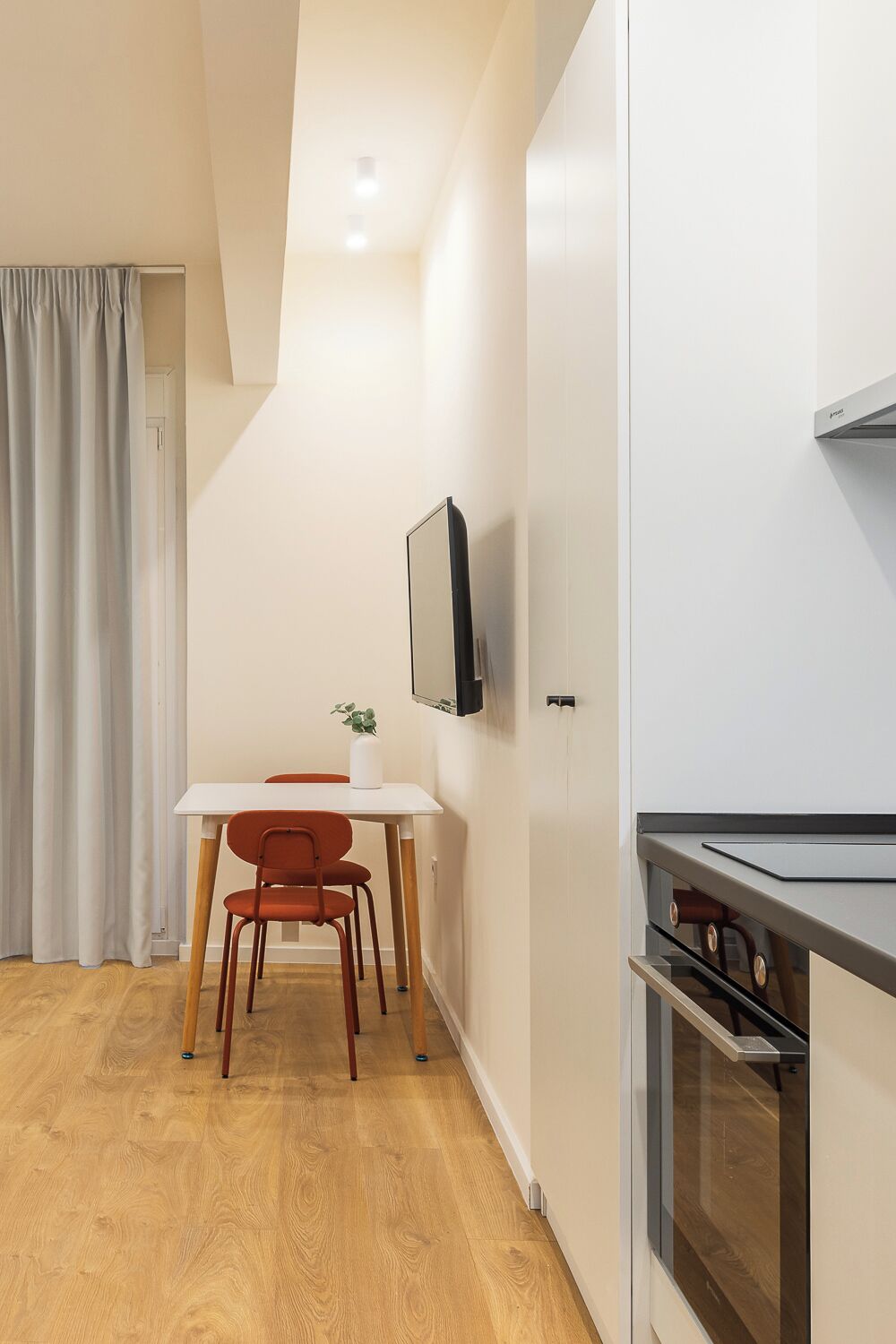 A modern kitchen with white cabinetry and a built-in oven.