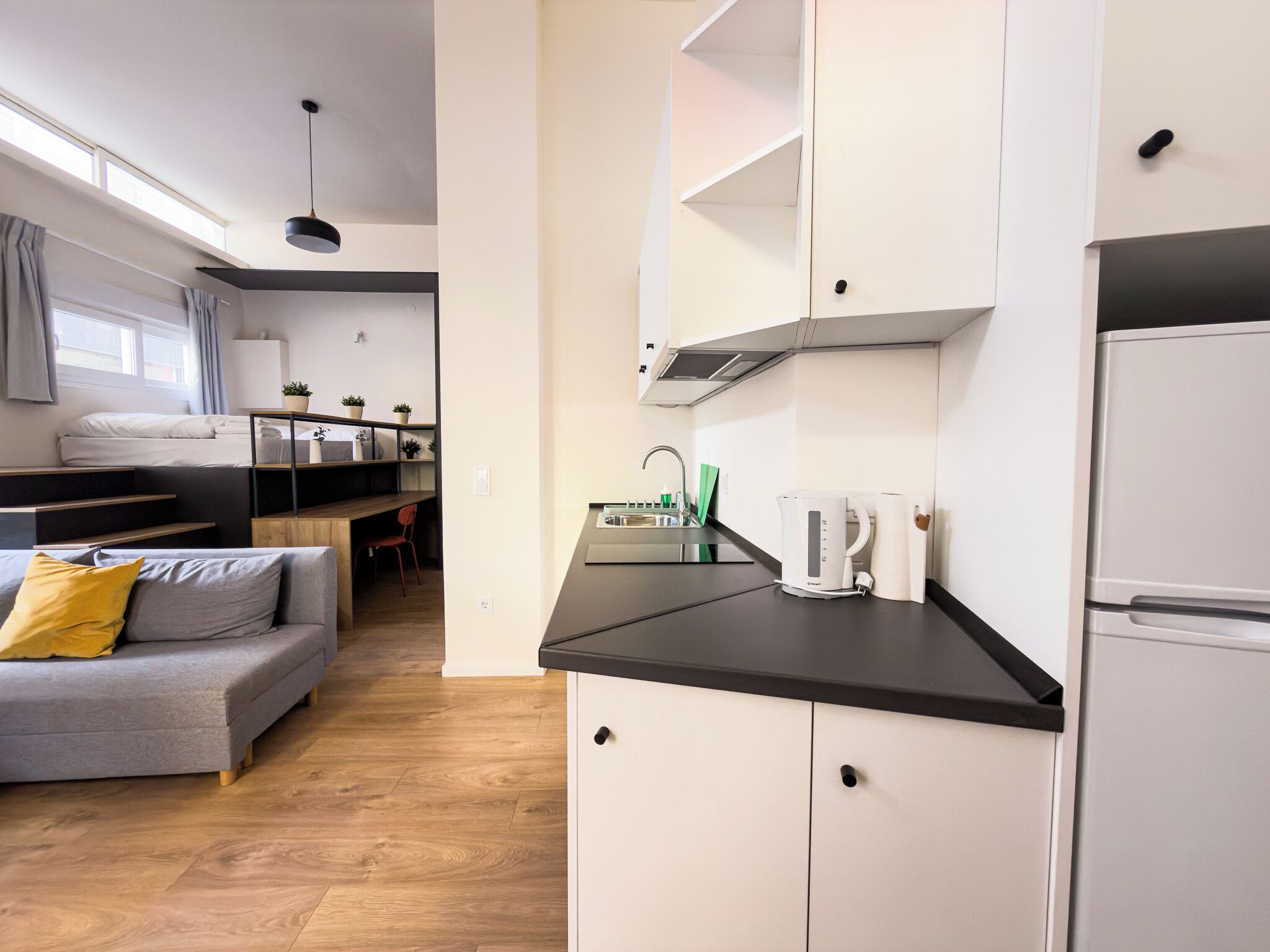 A compact, modern kitchenette with a built-in stove, a coffee maker, and a sink.