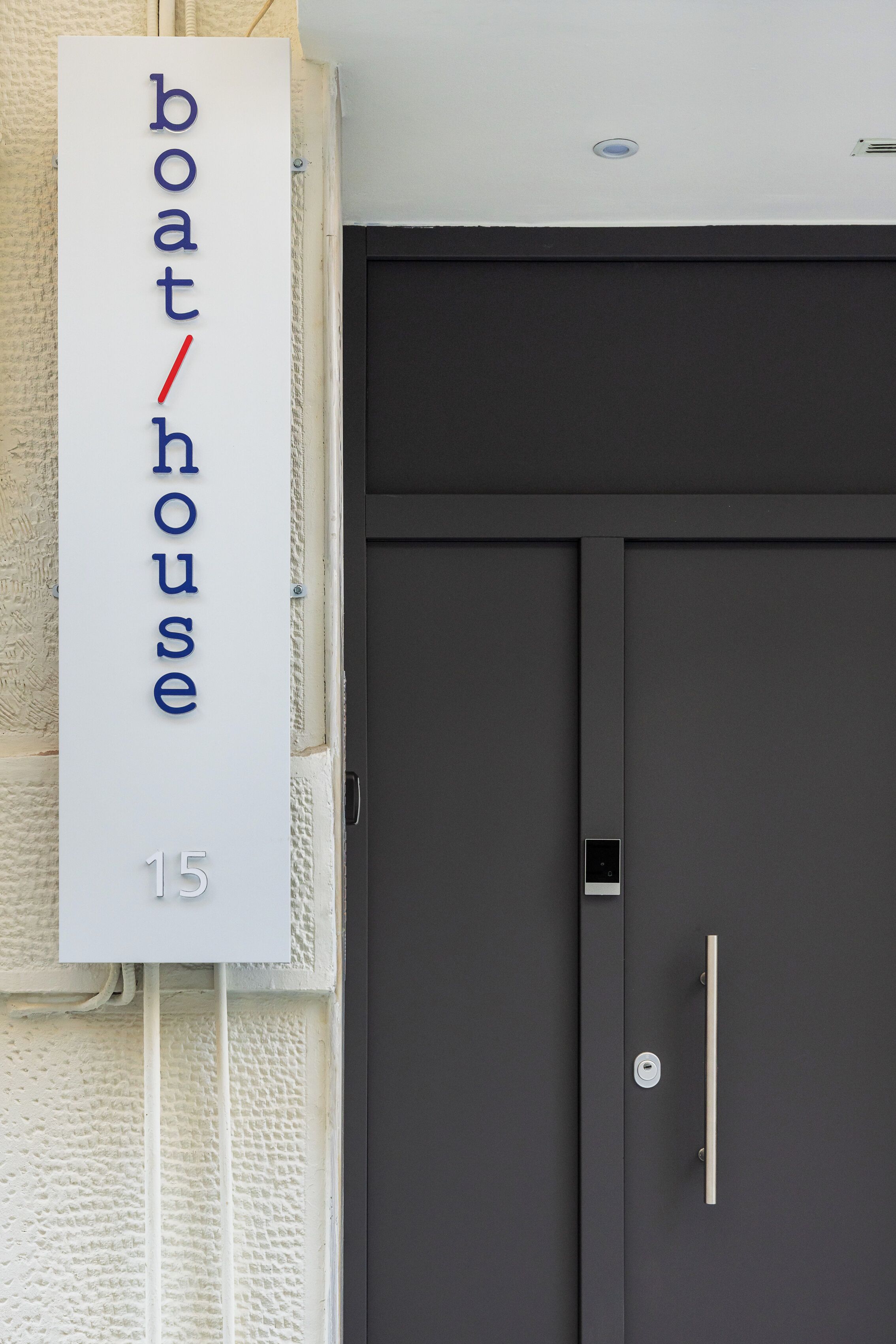 A building entrance with a sign reading "boathouse 15" and a modern door with a handle and lock.