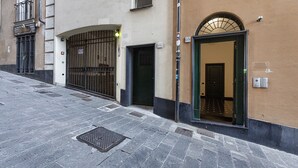 Un bâtiment doté d’une entrée fermée par un portail, d’une porte avec une enseigne et situé dans une rue pavée.