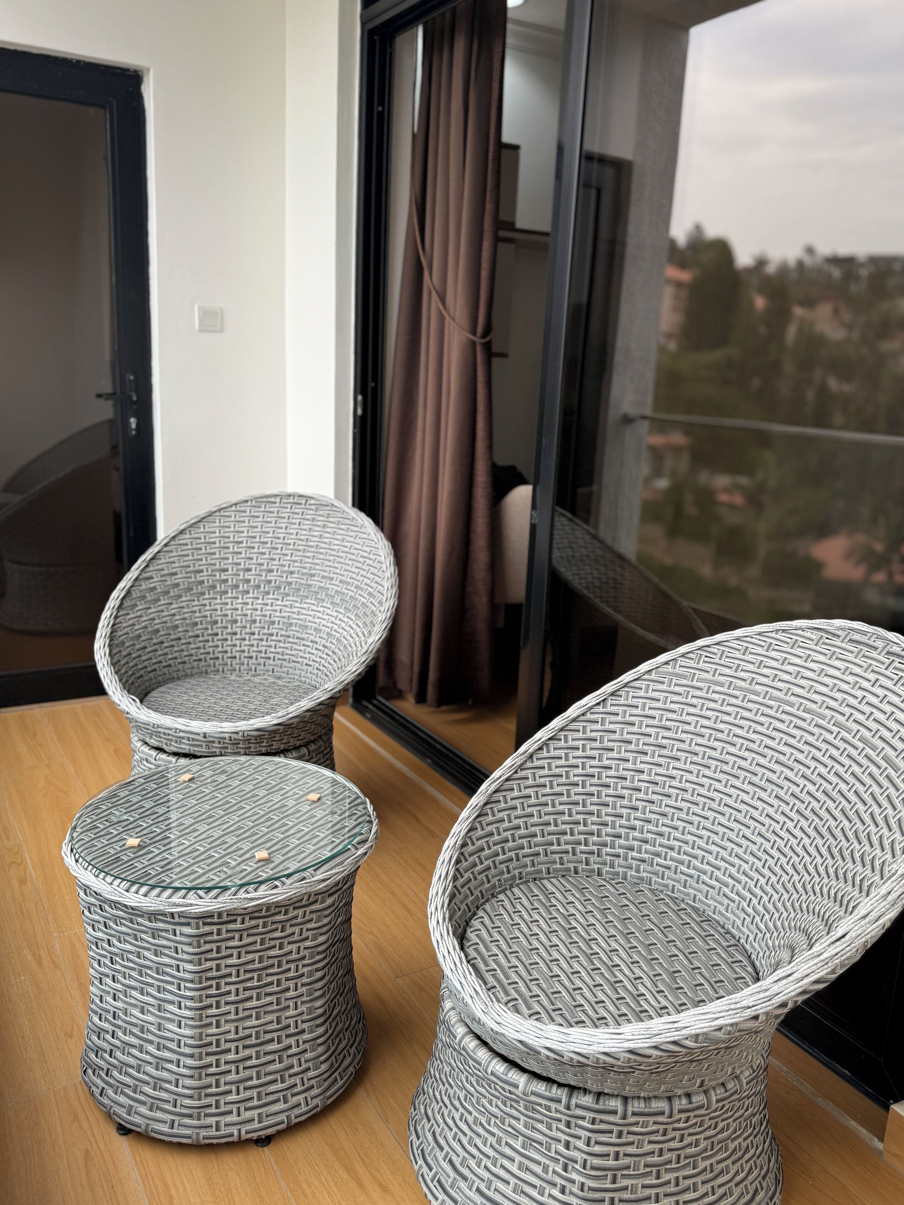 A balcony with wicker furniture, including two chairs and a small table.