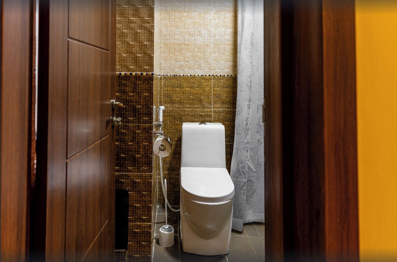 A bathroom with a toilet, a shower, and a toilet paper holder.