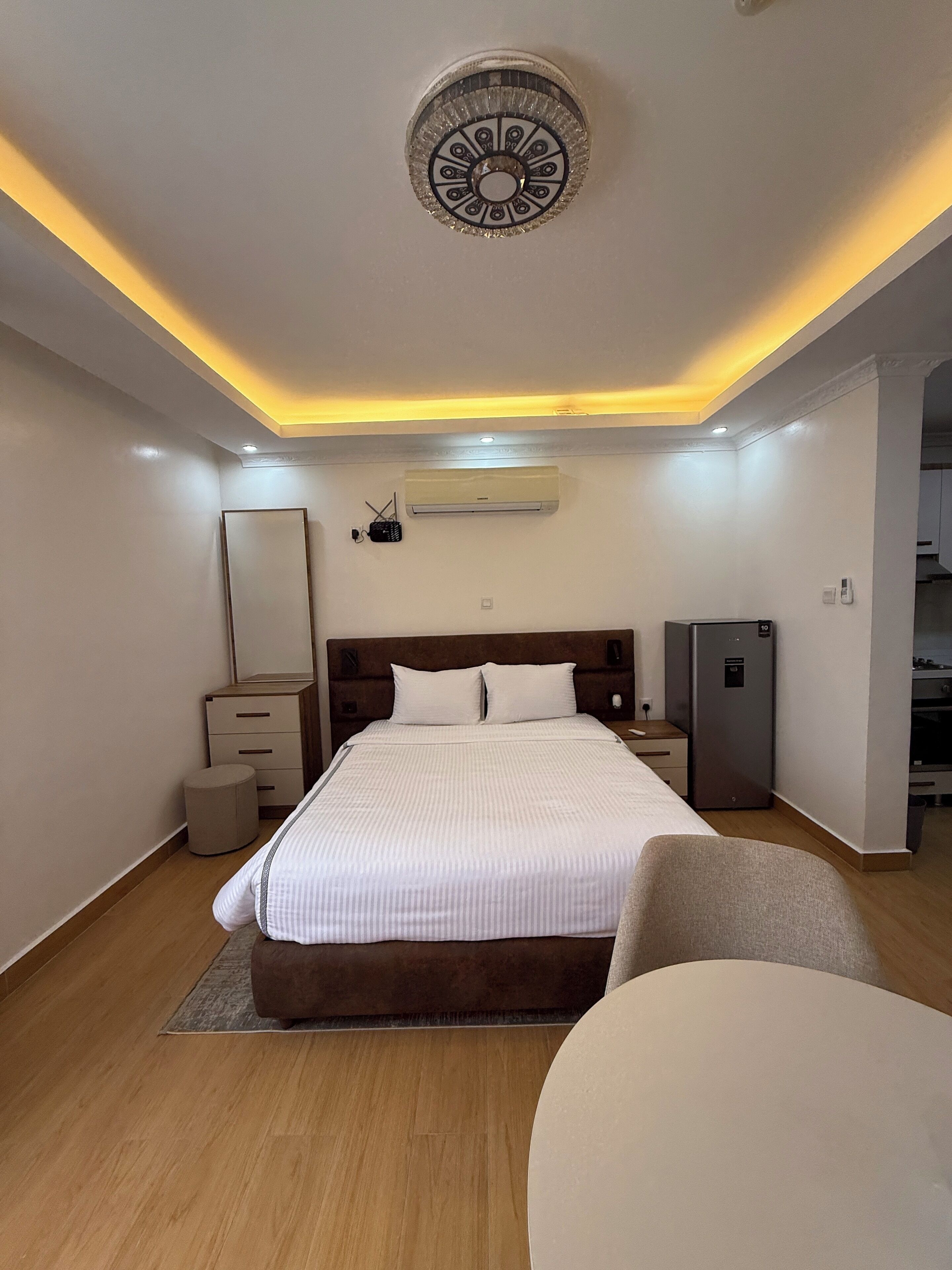 Ein modernes Schlafzimmer mit einem großen Bett, Nachttischen, einem Kleiderschrank und einer fest installierten Klimaanlage.