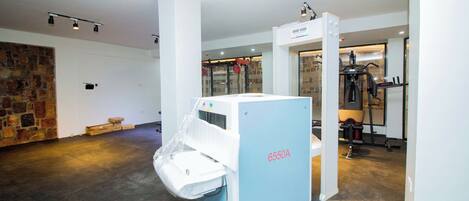 A room with a large industrial machine labeled 6550A, a stone wall, and a door leading to another area with exercise equipment.