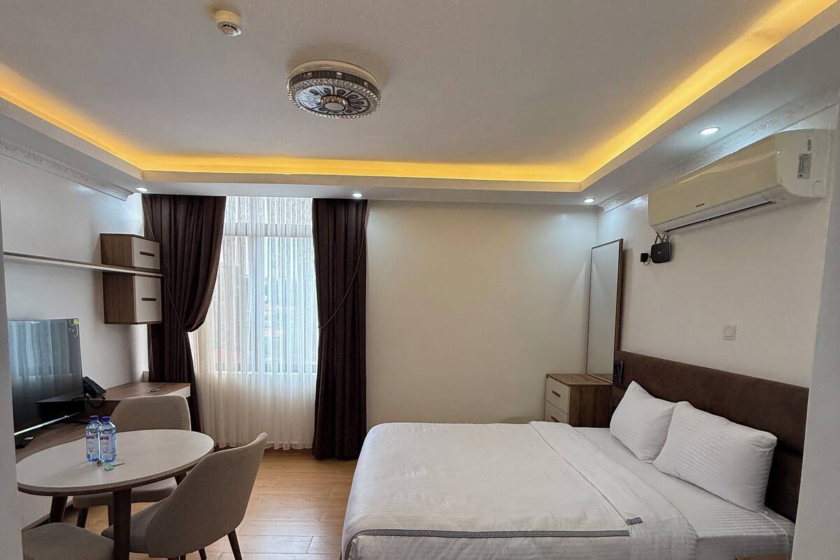 Une chambre d’hôtel équipée d’un lit, d’un bureau avec des chaises, d’une télévision et d’un appareil de climatisation.