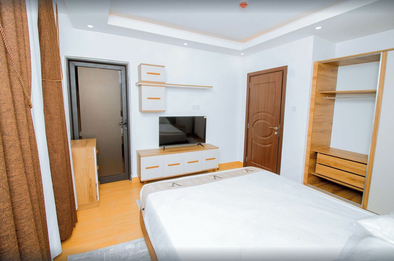 Un dormitorio moderno con cama, televisor, armario y escritorio.