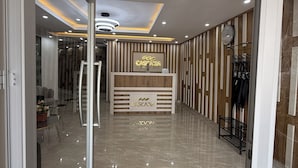 A hotel reception area with a modern design, featuring a reception desk, a clock, and a coat rack. - Cascadia Serviced Apartments (Kigali)