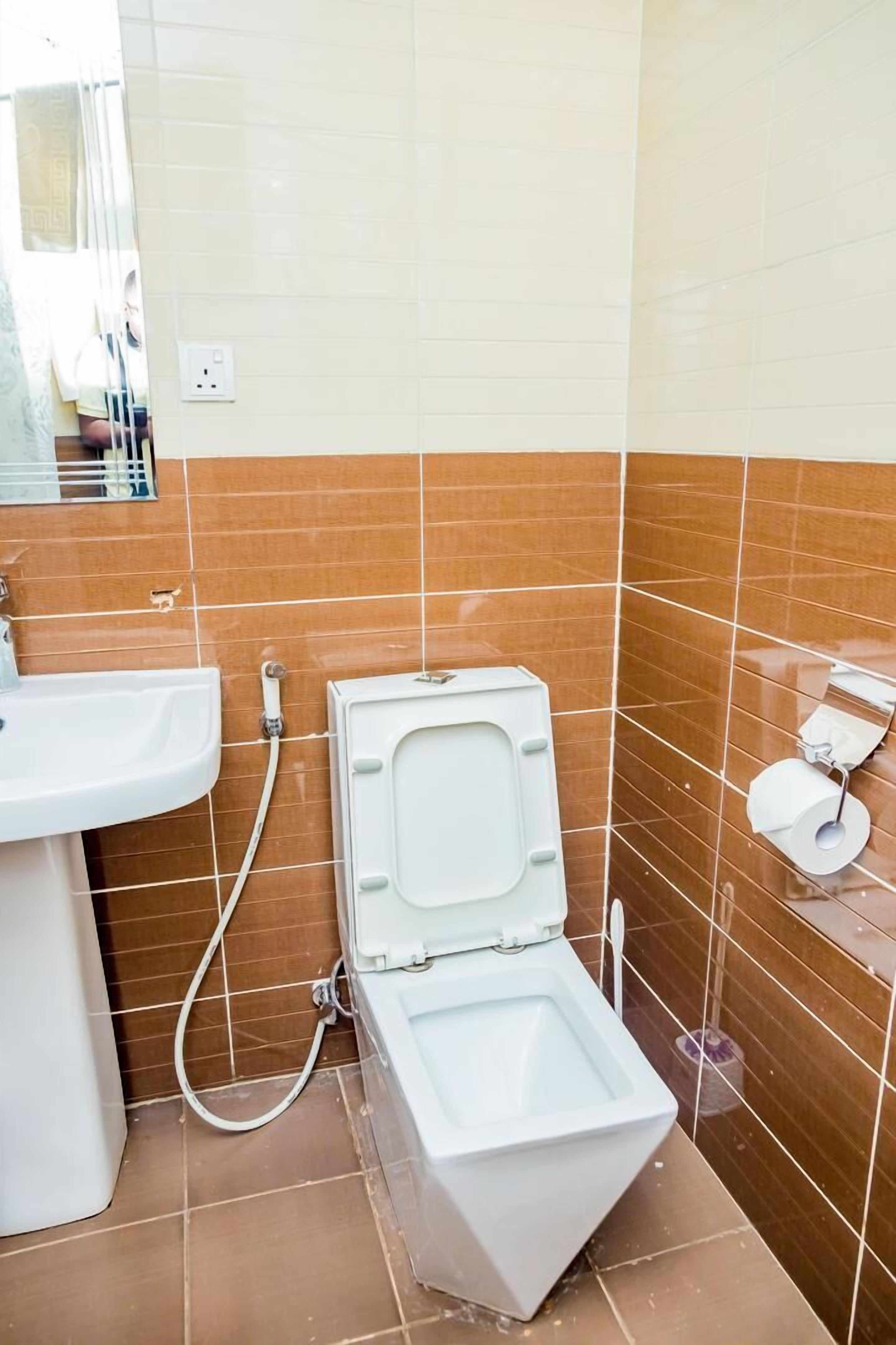 A bathroom with a toilet, sink, and a mirror.