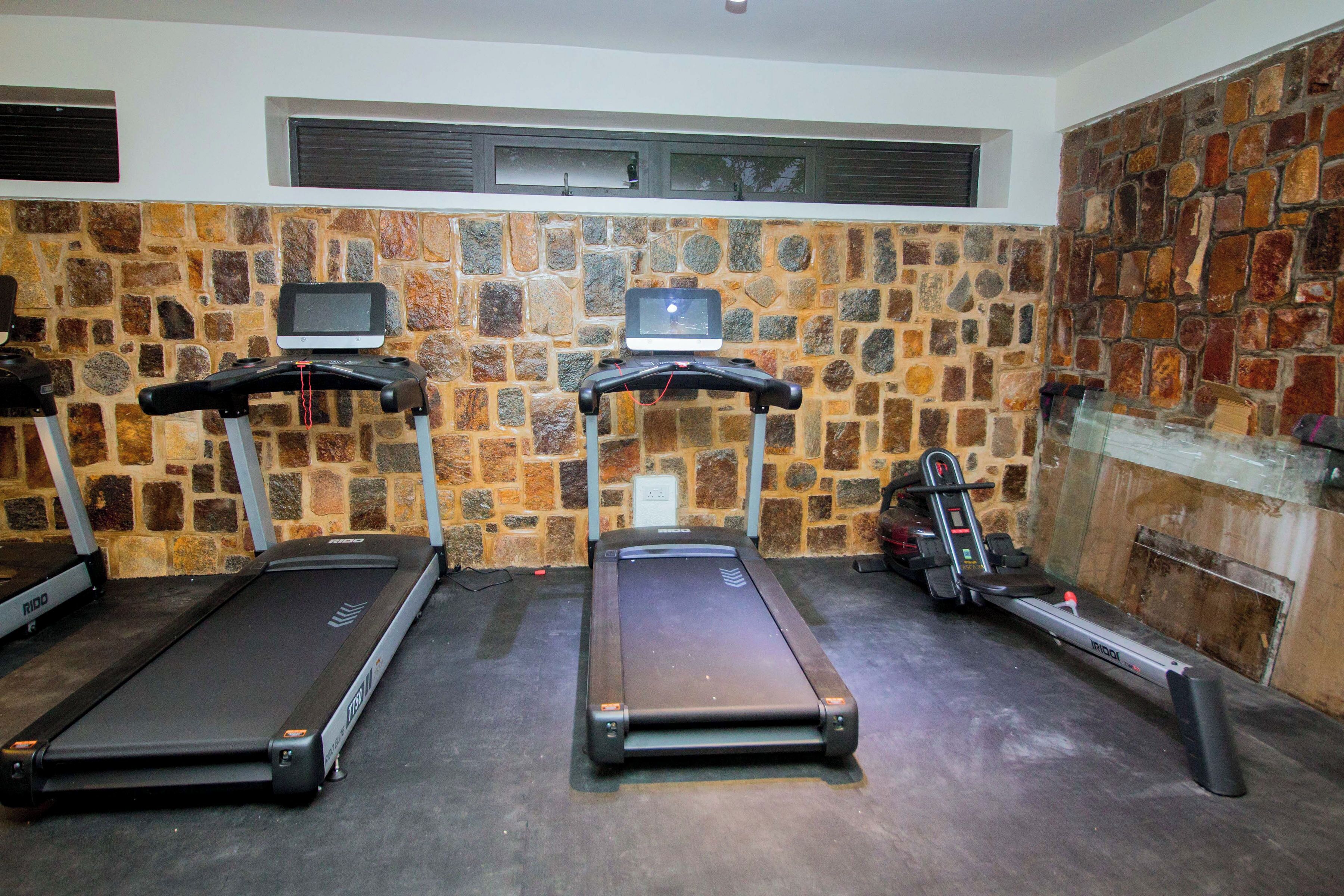 A gym with treadmills, a stationary bike, and a TV screen on the wall.