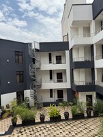 A multi-story building with a central spiral staircase, potted plants, and a checkered pavement area.
