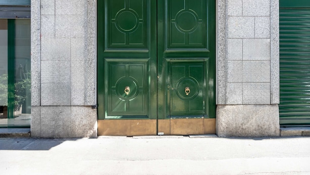 A set of green double doors with a circular design, set in a stone wall. - Casa Melzo Chic Apartment in Porta Venezia (Milan)