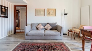 A living room with a grey sofa, two framed maps on the wall, a patterned rug, and a wooden table. - Casa Melzo Chic Apartment in Porta Venezia (Milan)