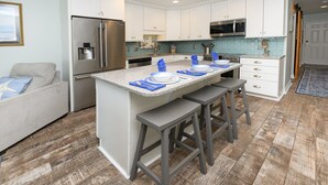 A modern kitchen with white cabinets, stainless steel appliances, and a granite countertop. - Oceanfront 2 BR Condo with Shared Pool! Channel Marker 302  (Surfside Beach)
