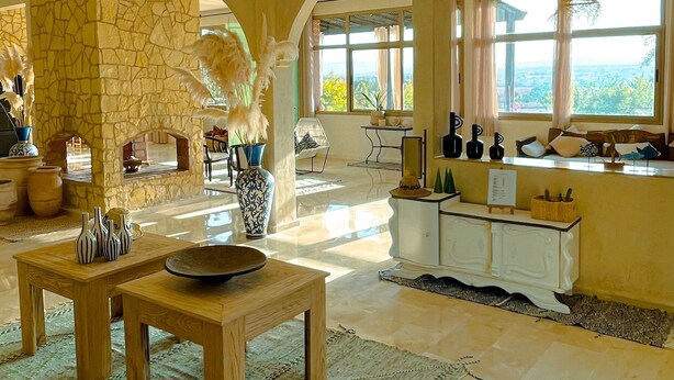 A spacious living area with a stone fireplace, a large window offering a view, and a well-lit ceiling with recessed lighting.