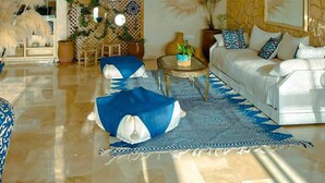A spacious living room with a white sofa, blue patterned cushions, a coffee table, and decorative plants.