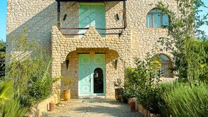 A stone building with a green door, a balcony, and a gravel driveway.