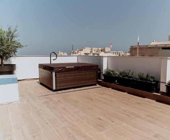 A rooftop terrace with a hot tub, potted plants, and a view of the city skyline. - King Charles Boutique (Valletta)