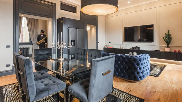 A modern dining area with a glass table, velvet chairs, and a dark ceiling light. - MEGA ROYAL SUITE (Città metropolitana di Roma Capitale)