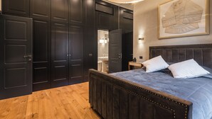 A bedroom with a large bed, dark wooden wardrobe, and a framed map on the wall. - MEGA ROYAL SUITE (Città metropolitana di Roma Capitale)