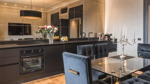 A modern kitchen with a central island, a dining area with a glass table, and a large mirror reflecting the space. - MEGA ROYAL SUITE (Città metropolitana di Roma Capitale)