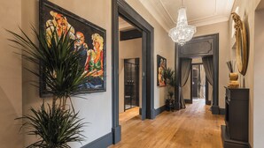 A hallway with wooden flooring, a chandelier, and framed artwork on the walls. - MEGA ROYAL SUITE (Città metropolitana di Roma Capitale)