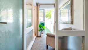 Ein Flur mit einer Schiebetür zu einem Balkon, einer Topfpflanze und einem beigen Sessel.