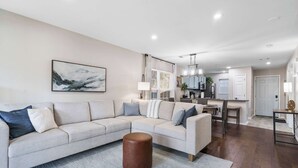 A modern living room with a sectional sofa, a coffee table, and a kitchen in the background.